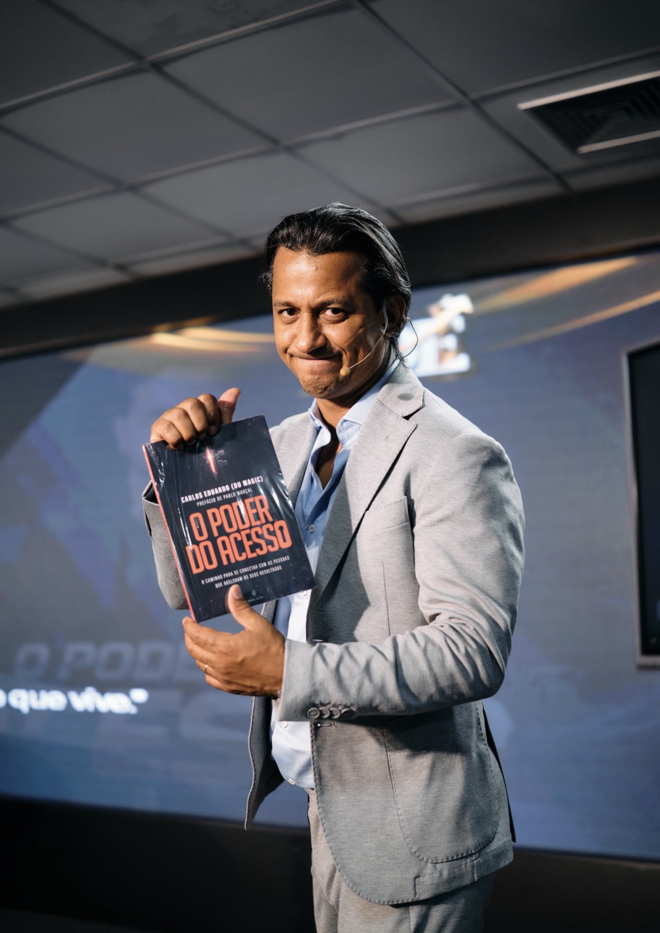 Carlos Eduardo (Du Magic) segurando o livro O Poder do Acesso durante uma palestra